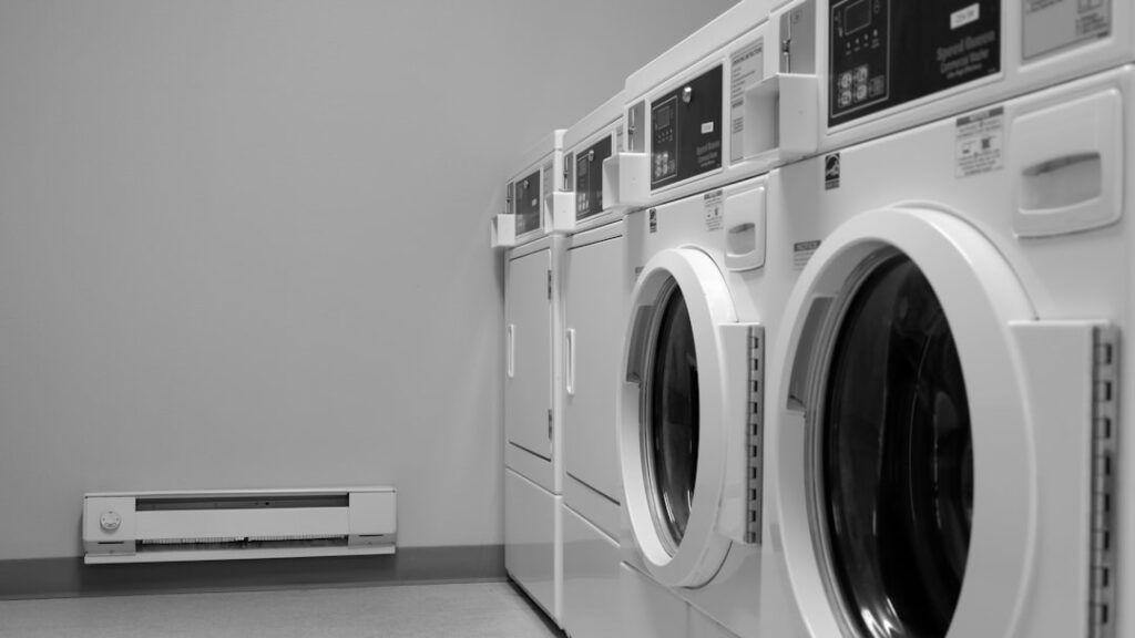 A person cleaning the lint trap of a front-load dryer in a residential laundry room.