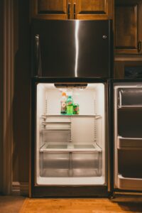 A person thoroughly cleaning removable fridge shelves at a kitchen sink.