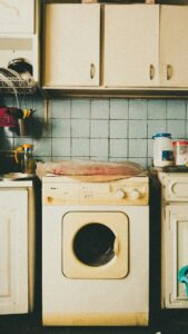 Open dishwasher being loaded with plates and glasses by a person in a home kitchen.