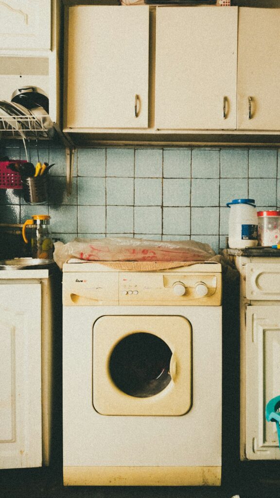 Open dishwasher being loaded with plates and glasses by a person in a home kitchen.
