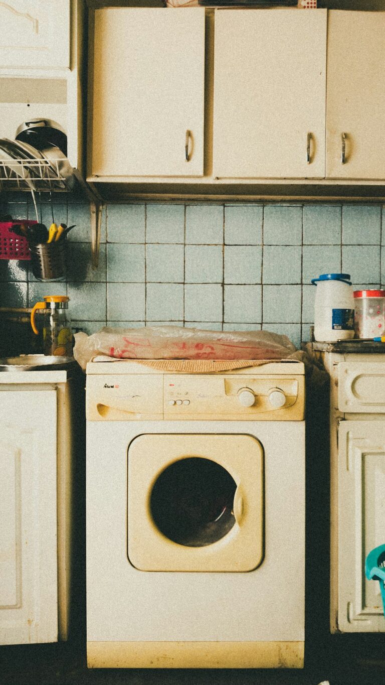 Open dishwasher being loaded with plates and glasses by a person in a home kitchen.