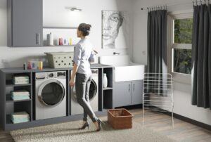 A homeowner cleans a refrigerator seal while checking nearby appliance connections in a bright kitchen.