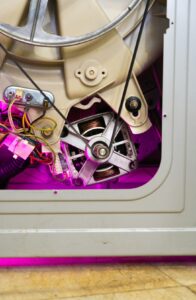 A homeowner checks a dryer lint screen beside an open laundry vent with damp clothes nearby.